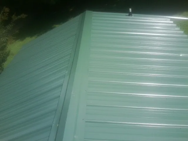 New green metal panels meeting at the ridge of a roof — Flat Roof Repair work by our crew in Winchester